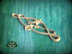 A decorative wooden carving resembling a heart shape is displayed against a teal-colored background.
