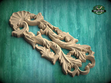 Load image into Gallery viewer, A carved wooden piece with intricate floral designs, displayed against a green background.
