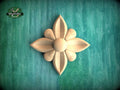 A wooden flower-shaped carving is displayed against a green background.