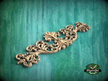 Load image into Gallery viewer, A decorative wooden carving with intricate scrollwork is displayed against a teal background.

