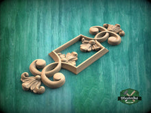 Load image into Gallery viewer, A decorative wooden carving with intricate floral and scrollwork designs is displayed against a green background.
