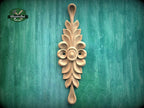 A decorative wooden carving with a floral design is displayed against a green background.