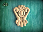 A wooden carving of a stylized flower or floral design is displayed against a green background.