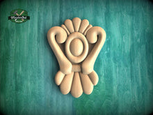 Load image into Gallery viewer, A wooden carving of a stylized flower or floral design is displayed against a green background.
