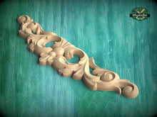 Load image into Gallery viewer, A decorative wooden carving with intricate floral and scrollwork designs is displayed against a green background.
