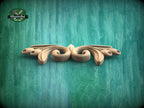 A decorative wooden carving with a floral design is displayed against a textured green background.
