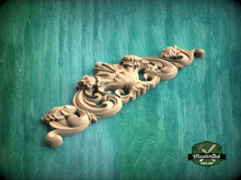 Load image into Gallery viewer, A decorative wooden carving with intricate floral and scrollwork designs is displayed against a green background.

