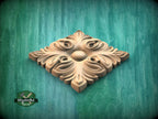 A decorative wooden panel with an intricate floral design, set against a green wooden background.