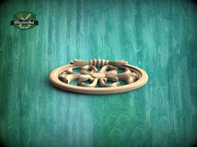 Load image into Gallery viewer, A wooden decorative piece with a floral design is displayed against a textured green background.
