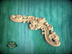 A decorative wooden carving with intricate swirls and curves is displayed against a teal background.
