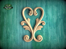 Load image into Gallery viewer, a decorative wooden heart-shaped object with intricate scrollwork and floral elements, set against a green textured background.
