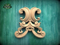 an ornate, carved wooden piece with intricate scrollwork and floral designs, set against a green background.