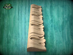 A wooden carving of a decorative element, possibly a decorative trim or molding, is displayed against a green background.