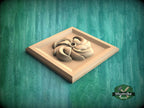 A wooden relief carving of a stylized flower or plant is displayed on a wooden surface against a green background.