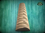 A wooden carving of a curved, textured piece of wood is displayed against a green background.