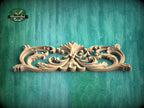 A decorative wooden carving with intricate scrollwork is displayed against a green wooden background.