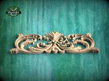 Load image into Gallery viewer, A decorative wooden carving with intricate scrollwork is displayed against a green wooden background.

