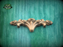 Load image into Gallery viewer, A decorative wooden carving with a floral design is displayed against a green wooden background.
