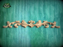 Load image into Gallery viewer, A decorative wooden carving with an ornate, floral design is displayed against a textured green background.
