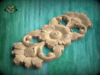 A wooden carving of a flower-like design with intricate details, displayed against a green background.