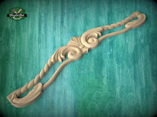 Load image into Gallery viewer, A wooden carving with intricate scrollwork and floral designs is displayed against a green wooden background.
