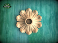 A wooden flower-shaped object is displayed against a green background.