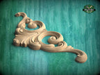 A decorative wooden carving with an intricate, swirling design is displayed against a teal background.