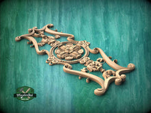Load image into Gallery viewer, A decorative wooden carving with intricate floral and scrollwork designs is displayed against a green background.
