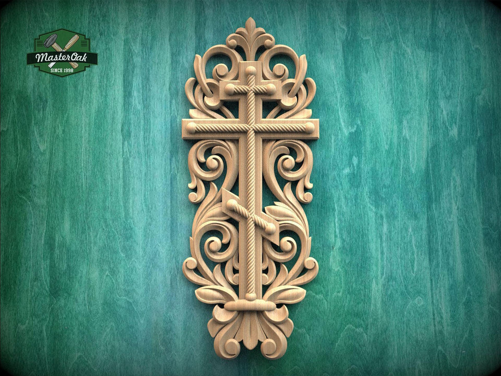 a decorative wooden cross with intricate carvings and scrollwork, mounted on a green wooden surface.