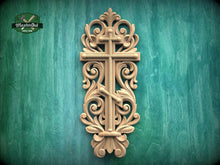 Load image into Gallery viewer, a decorative wooden cross with intricate carvings and scrollwork, mounted on a green wooden surface.
