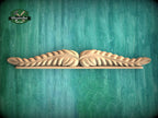 A wooden decorative leaf-like object is displayed against a green textured background.