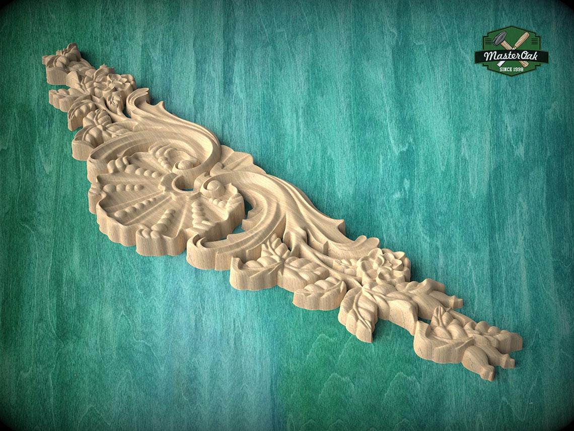 A decorative wooden carving with intricate floral and leaf patterns is displayed against a teal background.