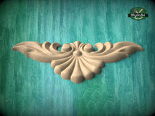 Load image into Gallery viewer, A wooden carving of a stylized shell or shell-like design is displayed against a teal-colored background.
