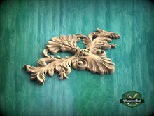 Load image into Gallery viewer, A decorative wooden carving with intricate floral and leaf-like patterns is displayed against a green textured background.
