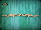 A decorative wooden carving with intricate scrollwork is displayed against a textured green background.