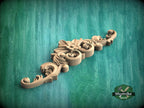 A decorative wooden carving with intricate scrollwork and floral elements is displayed against a green textured background.