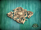 A decorative wooden carving with intricate scrollwork and floral patterns is displayed against a green background.