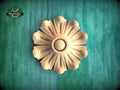 A wooden flower-shaped object is displayed against a green background.