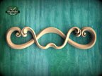 A wooden carving of a stylized mustache or goatee is displayed against a teal background.