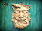 Carved wooden Green Man onlay featuring a forest face surrounded by oak leaves, with a bird resting above and a nest below, shown in natural wood finish on a textured background.