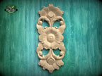 a decorative wooden carving of a flower on a green background.