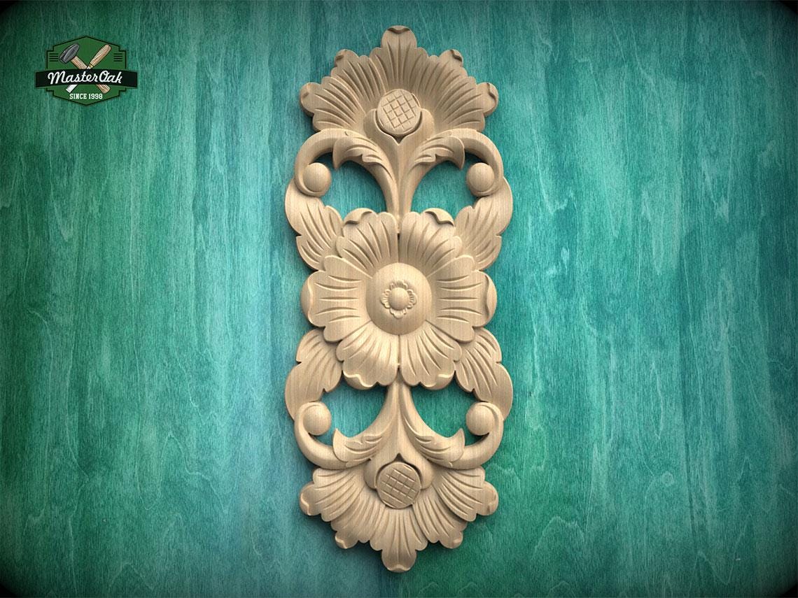 a decorative wooden carving of a flower on a green background.