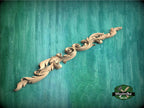 A decorative wooden carving in the shape of a scroll or ribbon is displayed against a green textured background.