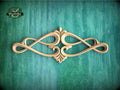 an ornate, carved wooden design with a floral motif, displayed against a green textured background.