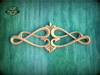 an ornate, carved wooden design with a floral motif, displayed against a green textured background.