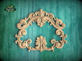 an ornate, carved wooden frame with intricate scrollwork and floral designs, set against a green background.