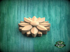 A wooden flower-shaped object is displayed against a green background.