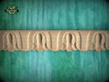 a decorative wooden border with a repeating pattern of carved shapes, set against a textured green background.