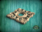 A decorative wooden panel with intricate floral and scrollwork designs, set against a green textured background.