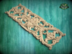 an ornate, carved wooden piece with intricate floral and scroll designs, set against a green background.